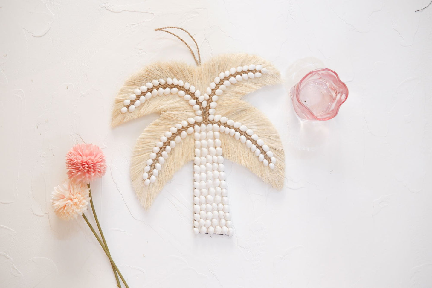 Palm tree sea shell wall decor featuring a pink glass and a flower, perfect for adding a touch of coastal and coquette charm to girls room, nursery room, and boho home decor