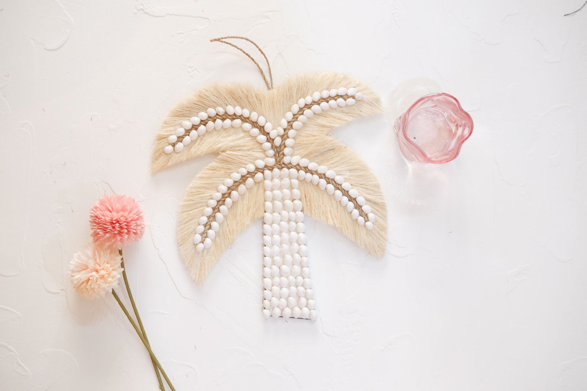 Palm tree sea shell wall decor featuring a pink glass and a flower, perfect for adding a touch of coastal and coquette charm to girls room, nursery room, and boho home decor