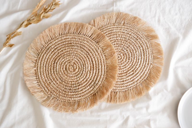 Handwoven boho fringe raffia placemat with natural fibers, perfect for adding rustic, eco-friendly charm to dining table settings