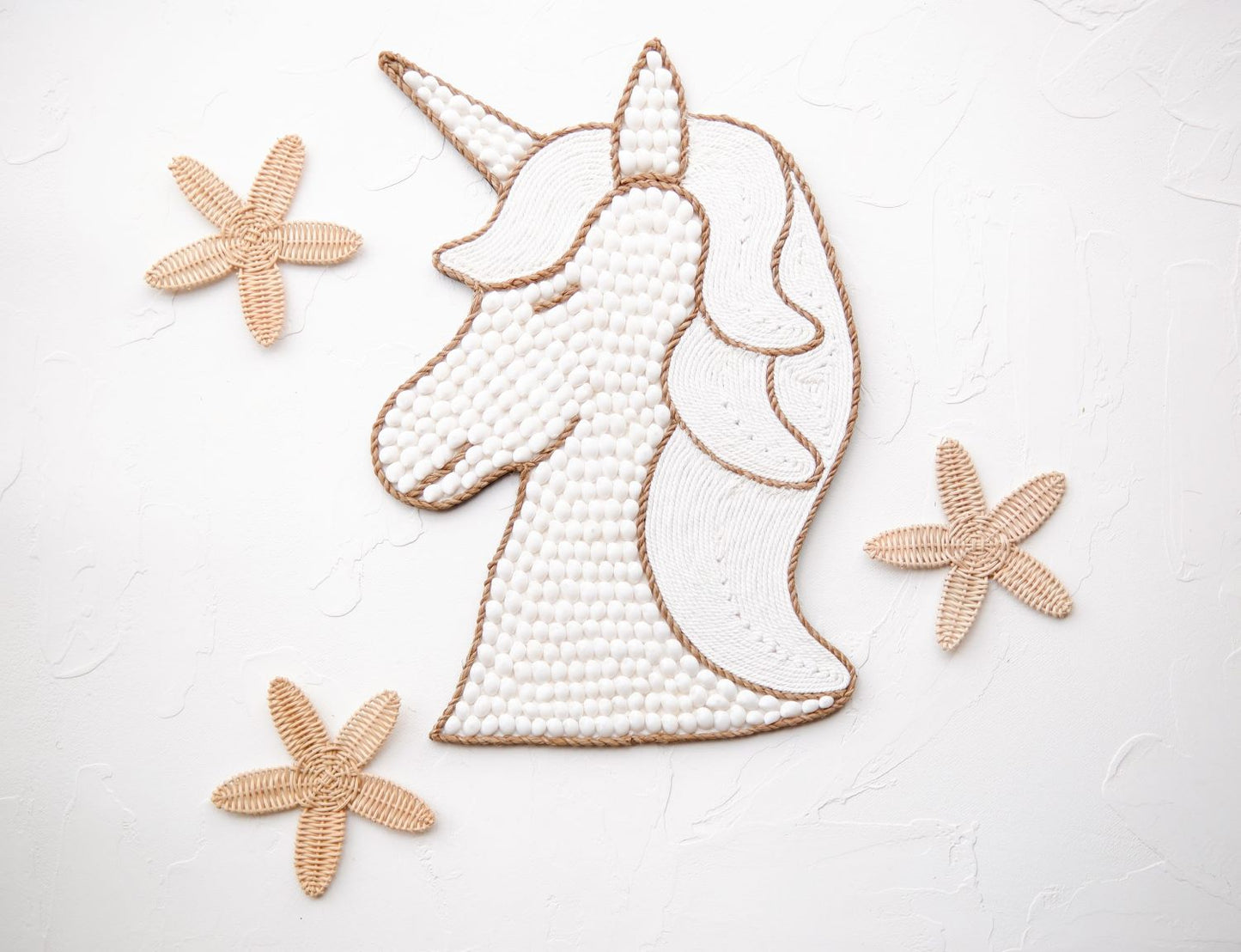 Unicorn wall decor made from white seashells combined with rattan starfish decor, perfect for a boho beach theme, coquette nursery, and little girls' room.